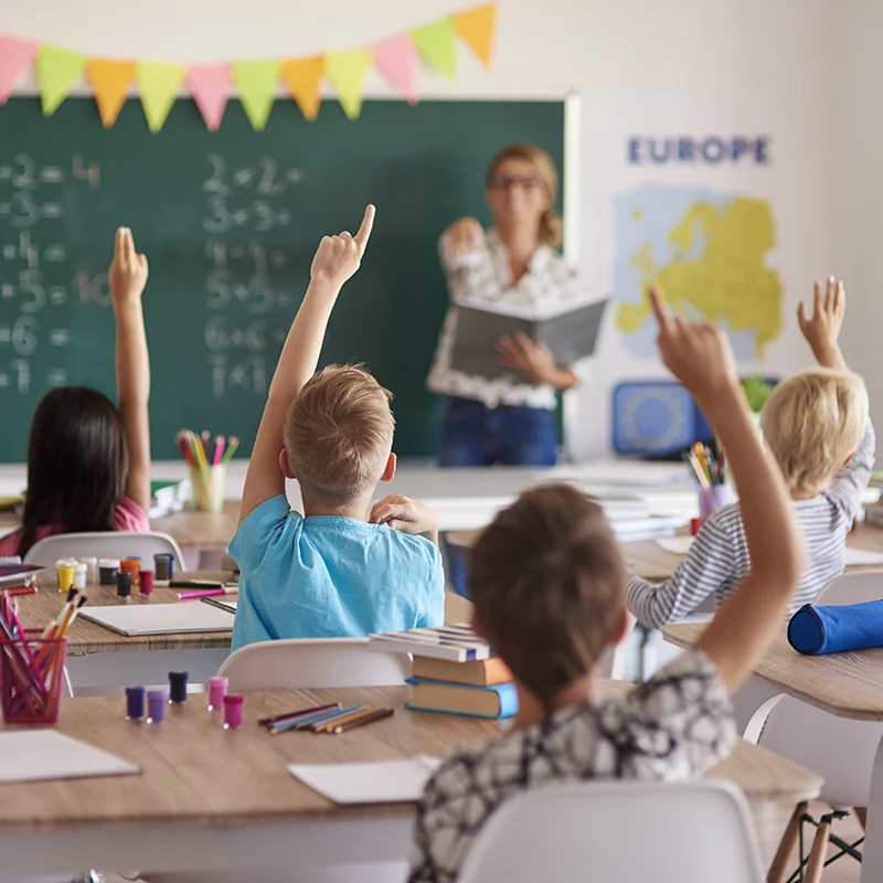 Gruppo di bambini in una classe che rispondono alla maestra